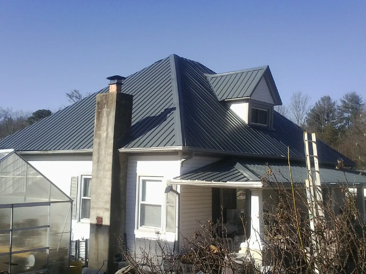 Dark blue standing seam metal roof on a white farmhouse with dormer — Slate & Tile Roof Repair by Roofing Brothers in Gibsonia