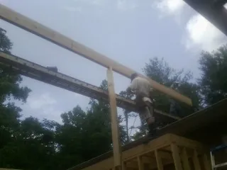 Carpenter setting a ridge beam over a new addition frame — Ice Dam Removal by Roofing Brothers in Gibsonia