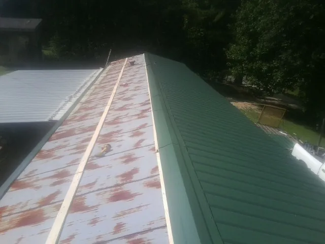 Old rusted panels beside newly installed green metal roofing — Wind Damage Roof Repair by Roofing Brothers in Gibsonia
