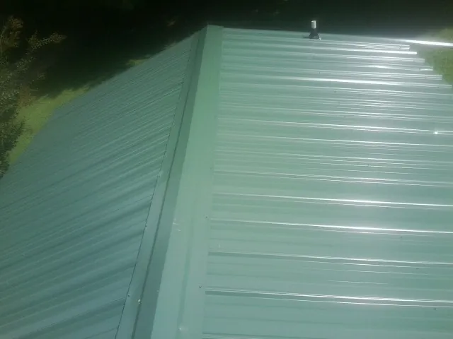 New green metal panels meeting at the ridge of a roof — Flat Roof Repair work by our crew in Gibsonia