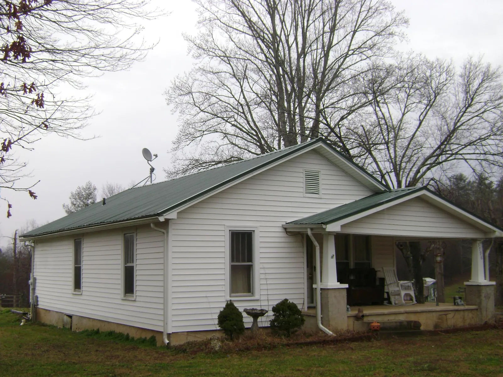 Green metal roof on a white bungalow with a side porch in Gibsonia