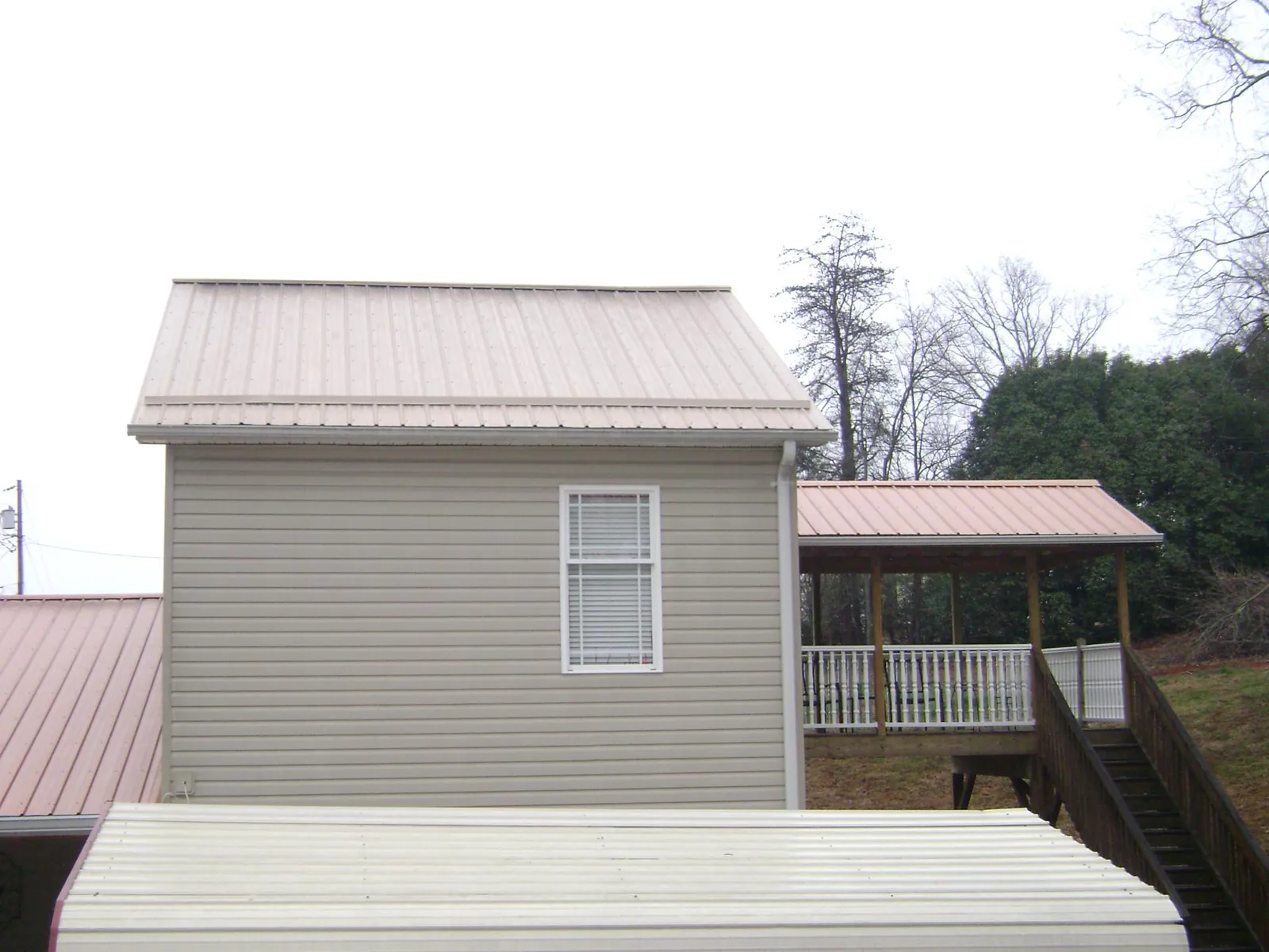 Tan metal roofs on a two story addition and attached porch, from a Roof Replacement job in Gibsonia