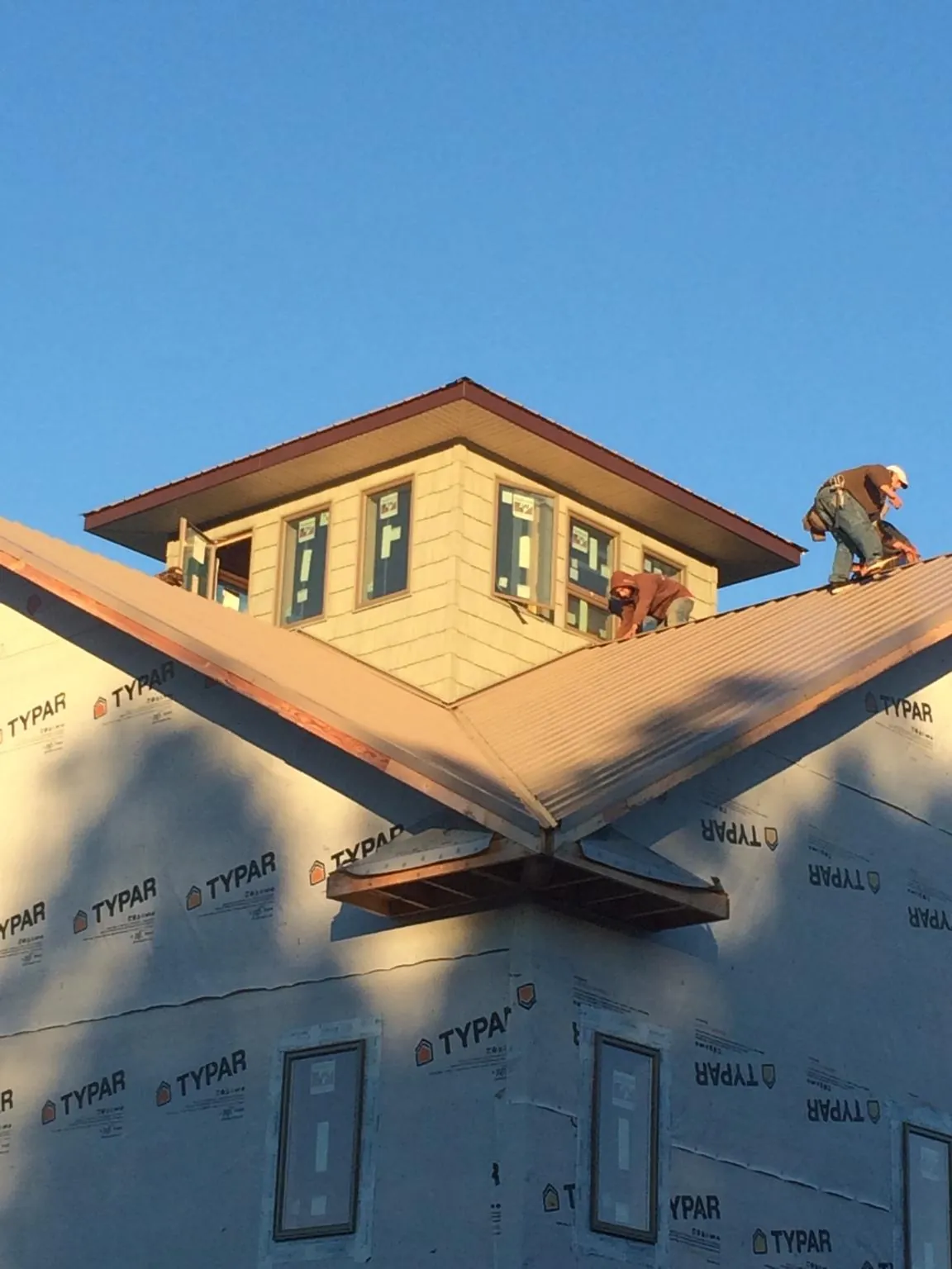 Roofers working around a rooftop cupola on a new metal roof at sunset — Roof Waterproofing in Gibsonia by Roofing Brothers